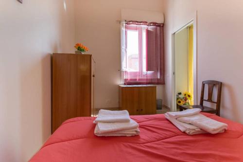 a bedroom with a red bed with two towels on it at The twins Rooms in Trapani 1 in Trapani