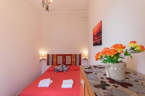 a bedroom with a red bed with a vase of flowers at The twins Rooms in Trapani 1 in Trapani