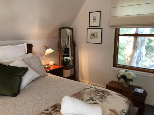 a bedroom with a bed and a window and a mirror at Coach House in Port Fairy