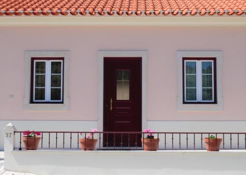 a white house with a black door and two windows at A Casa da Avó Ana in Arneiro das Milhariças