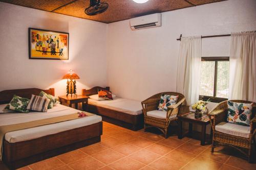 Cette chambre d'hôtel comprend deux lits, une table et des chaises. dans l'établissement Hibiscus Garden Inn, à Puerto Princesa