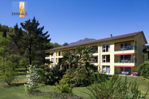 un edificio con un jardín delante de él en Parkhotel Emmaus - Casa del Sole, en Ascona