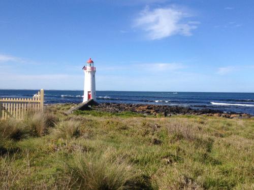 a lighthouse sitting on the side of the ocean at Coach House in Port Fairy