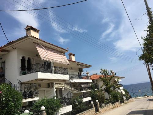 a white building with a balcony on a street at VillaKaliba BEACHFRONT HOUSE in Kalives Poligirou