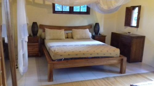 - une chambre avec un lit et un cadre de lit en bois dans l'établissement Shalana Homestay- formerly Teka Teki House, à Seminyak