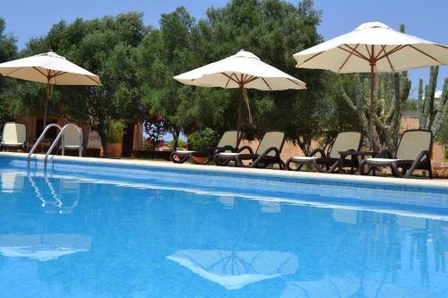 a swimming pool with chairs and umbrellas at Agroturismo Finca Son Sala in Campos