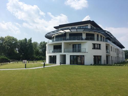 a large white building with a green field in front of it at Apartman Balaton in Keszthely
