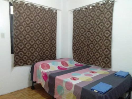 una piccola camera da letto con un letto con copriletto colorato di Budget Studio Unit in Makati a Manila