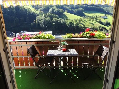 a table and chairs on a balcony with flowers at Gästehaus und Ferienwohnung Bächle in Bad Peterstal