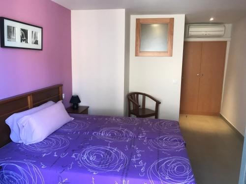 sypialnia z fioletowym łóżkiem i białą poduszką w obiekcie Apartaments Ca L'Albert w mieście Pobla de Segur