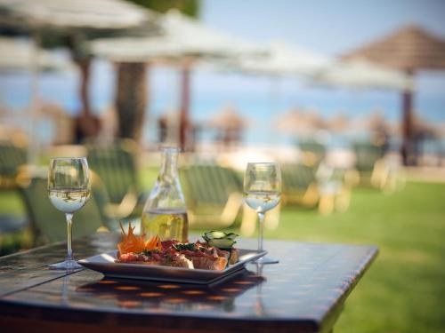 un piatto di cibo e due bicchieri di vino su un tavolo di Plaka Beach Resort a Vasilikós