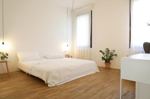 a white bedroom with a bed and two windows at Welc-oM Casa Anna in Padova