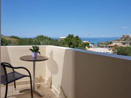 a small table on a balcony with a view of the ocean at Plaka Beach Resort in Vasilikos