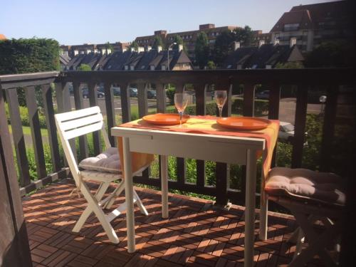 une table avec deux verres et deux chaises sur un balcon dans l'établissement Le Studio 102, à Villers-sur-Mer