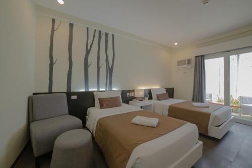 a hotel room with two beds and a chair at One Manalo Place in Puerto Princesa City