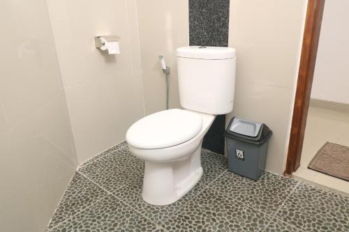 a bathroom with a white toilet and a trash can at De Loran Hotel in Banjar