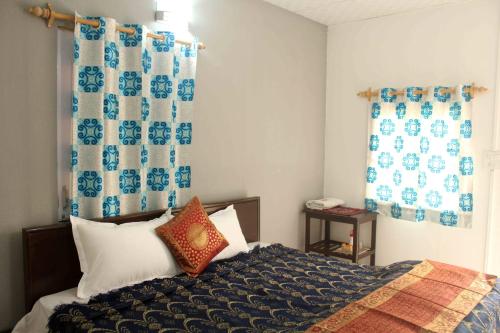a bedroom with a bed and blue and white curtains at Comfort Point Bed & Breakfast in New Delhi