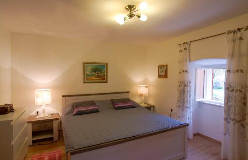 a bedroom with a bed with two lamps and a window at Holiday Homes Mirjana in Mošćenička Draga