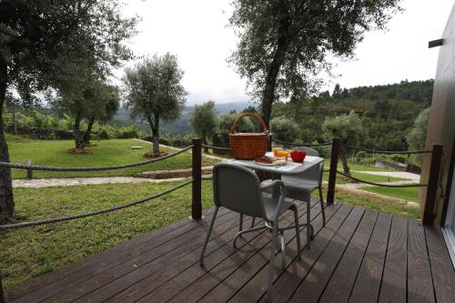 a table and chair on a deck with a view of a field at Ternaldo Agroturismo & Relax in Arco de Baúlhe