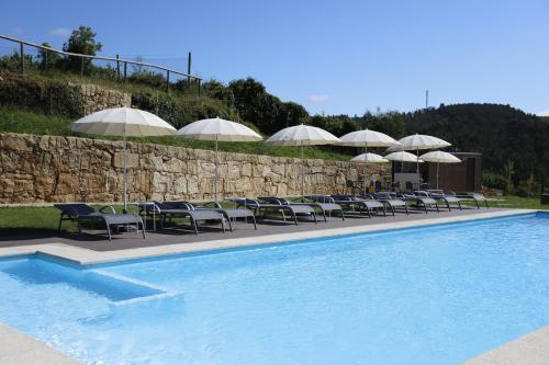 a row of chairs and umbrellas next to a swimming pool at Ternaldo Agroturismo & Relax in Arco de Baúlhe