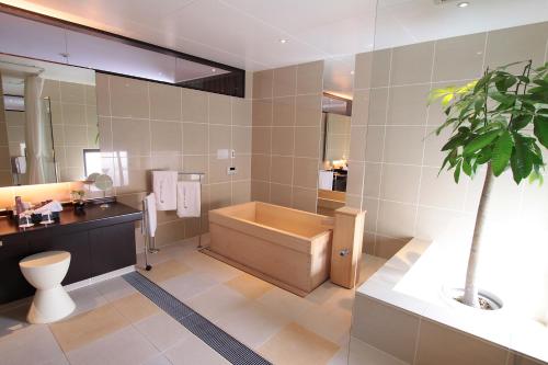 La salle de bains est pourvue d'une baignoire et d'une plante en pot. dans l'établissement Kizashi The Suite 京都祇園, à Kyoto