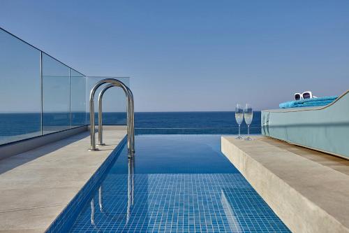 a swimming pool with wine glasses next to the ocean at Seafront Apartments by Myseasight in Hersonissos