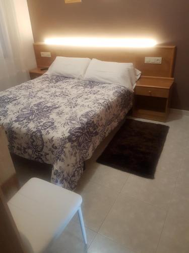 a bedroom with a bed with a blue and white blanket at Hostal Xaraiba in Sanxenxo