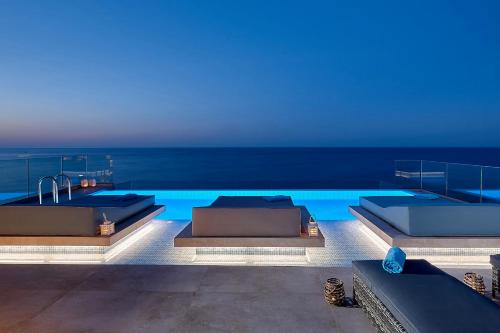 a swimming pool with two beds and the ocean at Seafront Apartments by Myseasight in Hersonissos