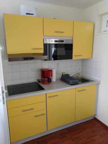 ヴィーク・アウフ・リューゲンにあるWohnung am Boddenのキッチン(黄色のキャビネット、シンク付)