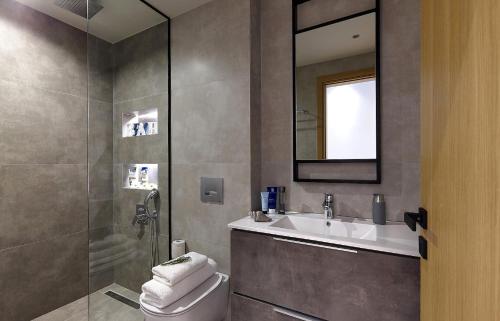 a bathroom with a sink and a toilet and a mirror at Seafront Apartments by Myseasight in Hersonissos