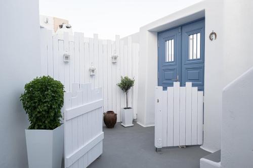 a white hallway with a blue door and plants at Santo Castello in Akrotiri