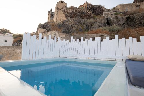 a white fence next to a swimming pool with a building at Santo Castello in Akrotiri