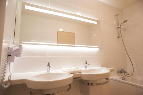 a white bathroom with two sinks and a mirror at Hotel Spa Le Relais Du Bellay in Montreuil-Bellay