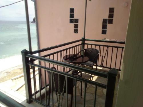 a balcony with a table and a chair and the ocean at Nissaki Guesthouse in Keramídhion