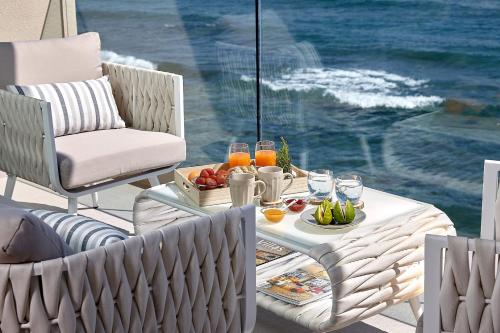a table with a tray of fruit and drinks on a patio at Seafront Apartments by Myseasight in Hersonissos
