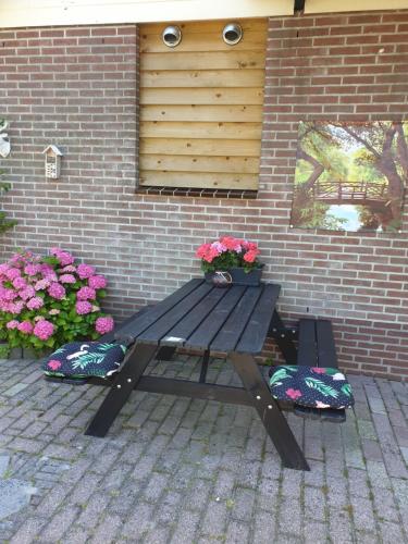 a picnic table in front of a brick wall with flowers at Logeren op Dijk43 in Broek op Langedijk