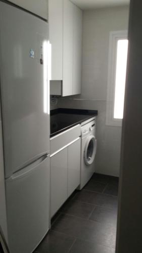 a kitchen with a white refrigerator and a washing machine at Apartamentos La Vaguada Suites in Madrid