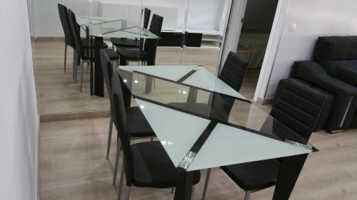 a dining room with glass tables and black chairs at Apartamentos La Vaguada Suites in Madrid