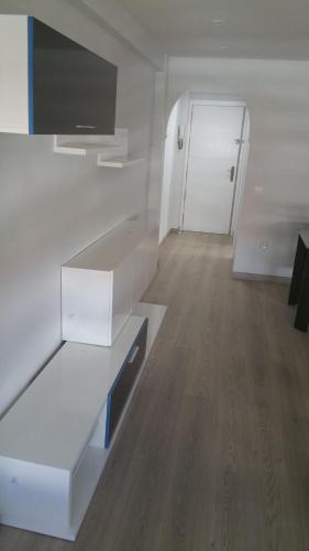 a room with white furniture and a hallway with a door at Apartamentos La Vaguada Suites in Madrid