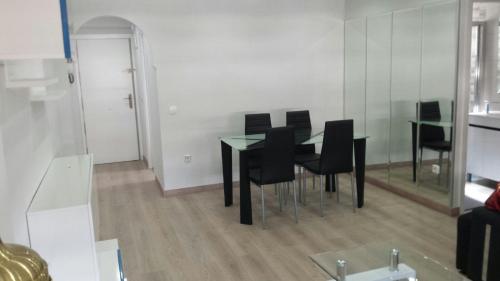 a dining room with a black table and black chairs at Apartamentos La Vaguada Suites in Madrid