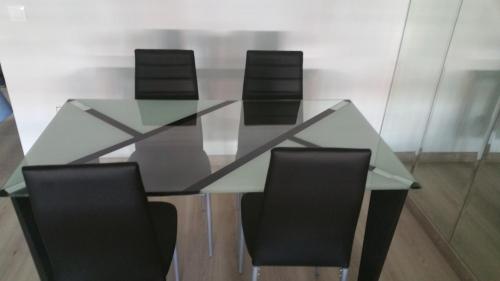 a glass table with four black chairs around it at Apartamentos La Vaguada Suites in Madrid