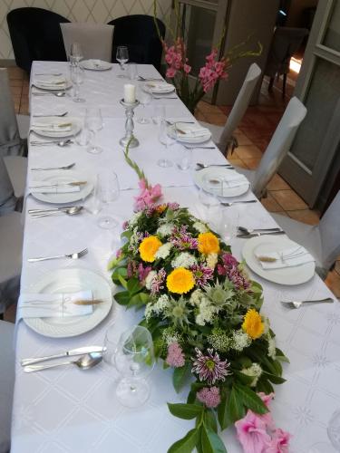 a long white table with a flower arrangement on it at Dworek 1885 in Ostrzeszów