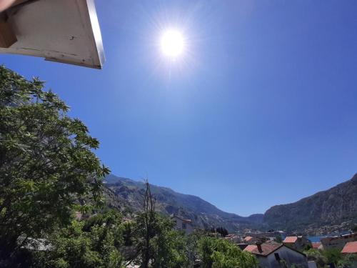 a sun in the sky over a town with mountains at Apartments Dakovic in Kotor