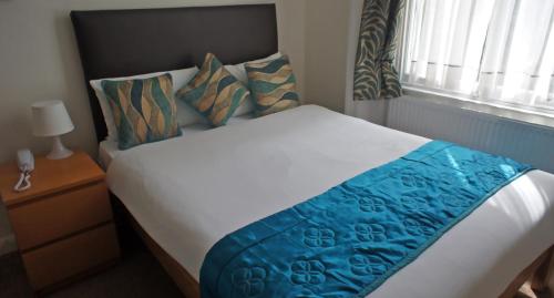 a bedroom with a bed with blue sheets and a window at Westpoint Hotel in London