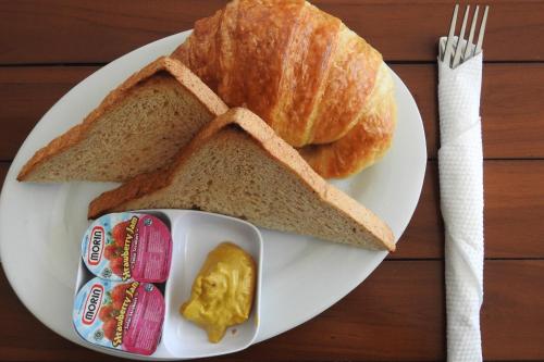 un plato blanco con pan, mantequilla y un cruasán en D'Batur Hotel, en Senggigi 