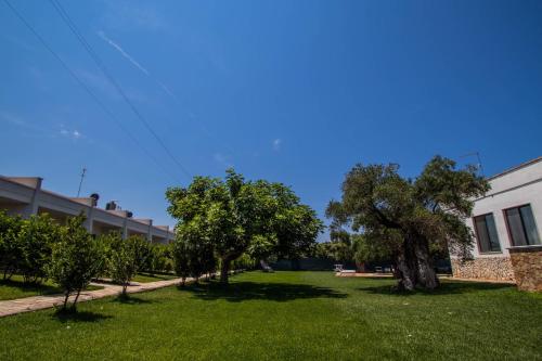 a green yard with trees and a building at Hotel Eden in Carovigno