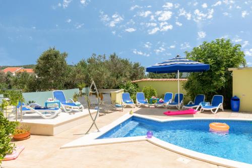 een zwembad met stoelen en een parasol bij Apartments Petra in Trogir