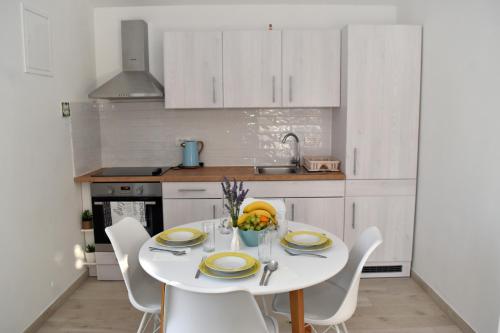 eine weiße Küche mit einem weißen Tisch und Stühlen in der Unterkunft Happy House in Zadar