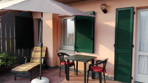einen Tisch, Stühle und einen Regenschirm auf einer Terrasse in der Unterkunft Sweet Home Casa Vacanze "La Terrazza" in Rovetta