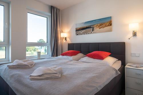 ein Schlafzimmer mit einem großen Bett mit roten Kissen darauf in der Unterkunft Appartement "Saphir" mit Penthouseflair - Oase am Haff in Garz